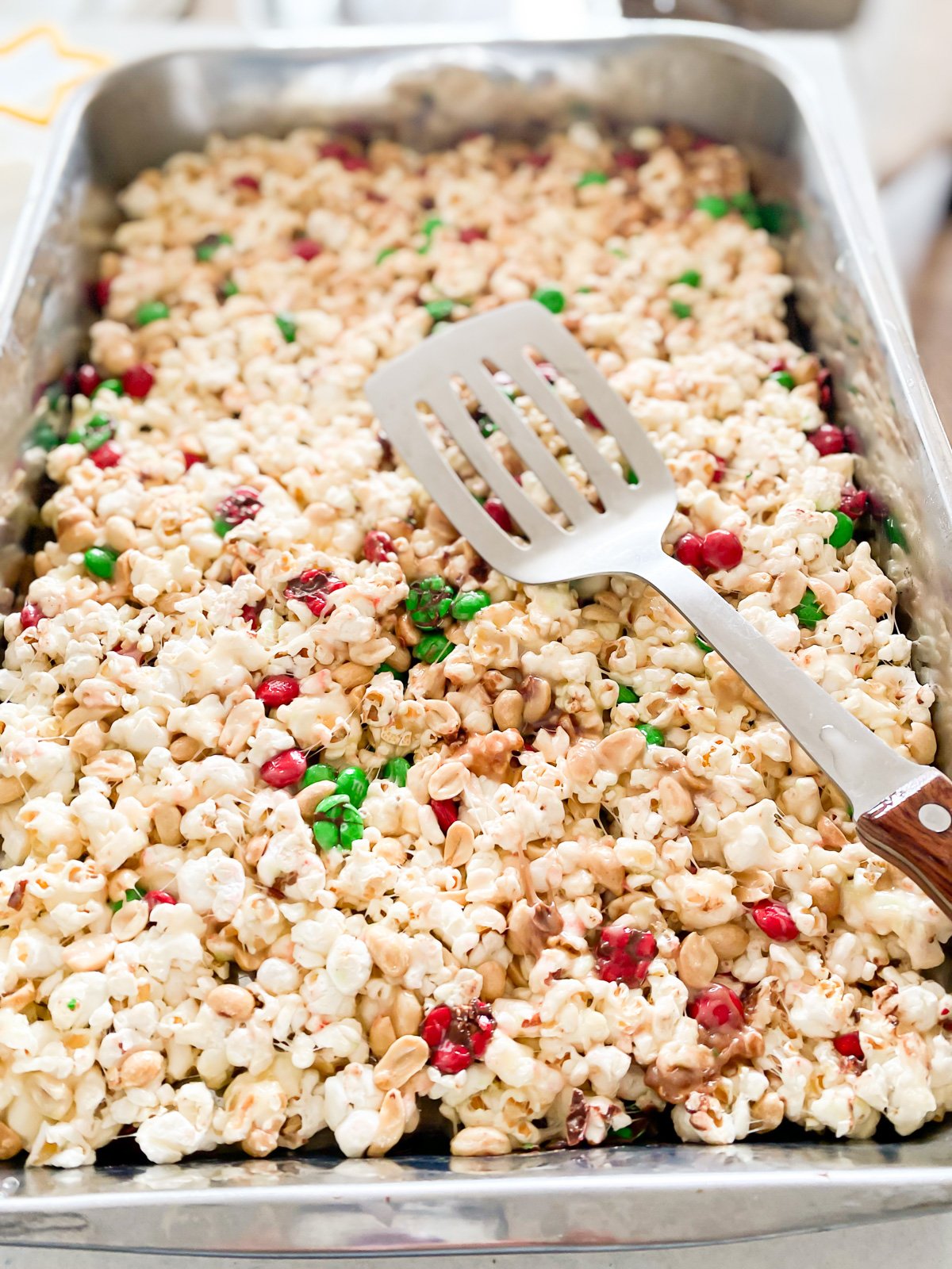 menekan campuran popcorn, marshmallow, kacang tanah, dan mentega ke dalam loyang.