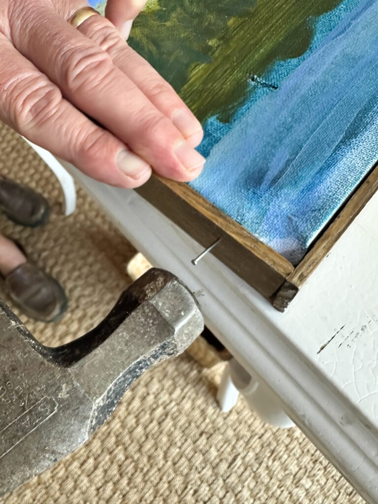 Hammering di dalam kuku untuk menempelkan bingkai kayu ke kanvas seni
