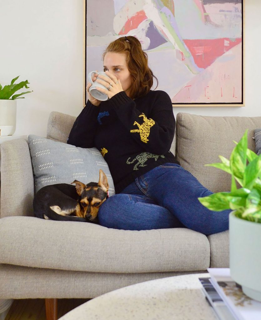 Sherry duduk dengan anjing sen di sofa minum teh
